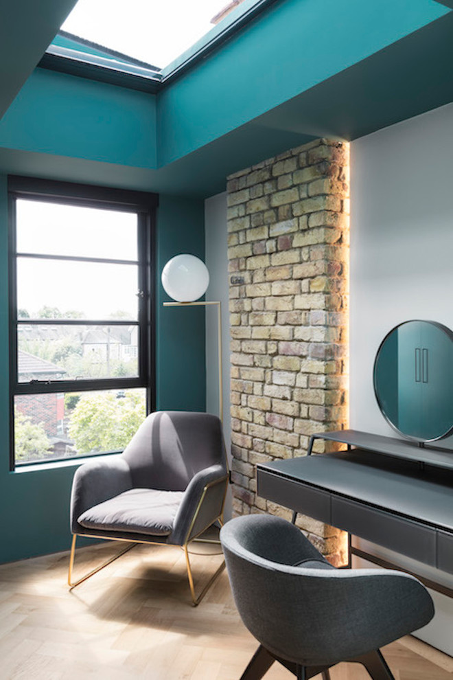 Contemporary bedroom in London with green walls, light hardwood floors, no fireplace and beige floor.