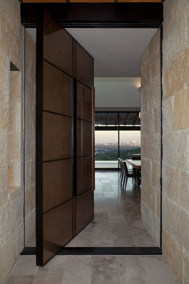 Inspiration for a large contemporary front door in Austin with beige walls, limestone floors, a pivot front door and a brown front door.