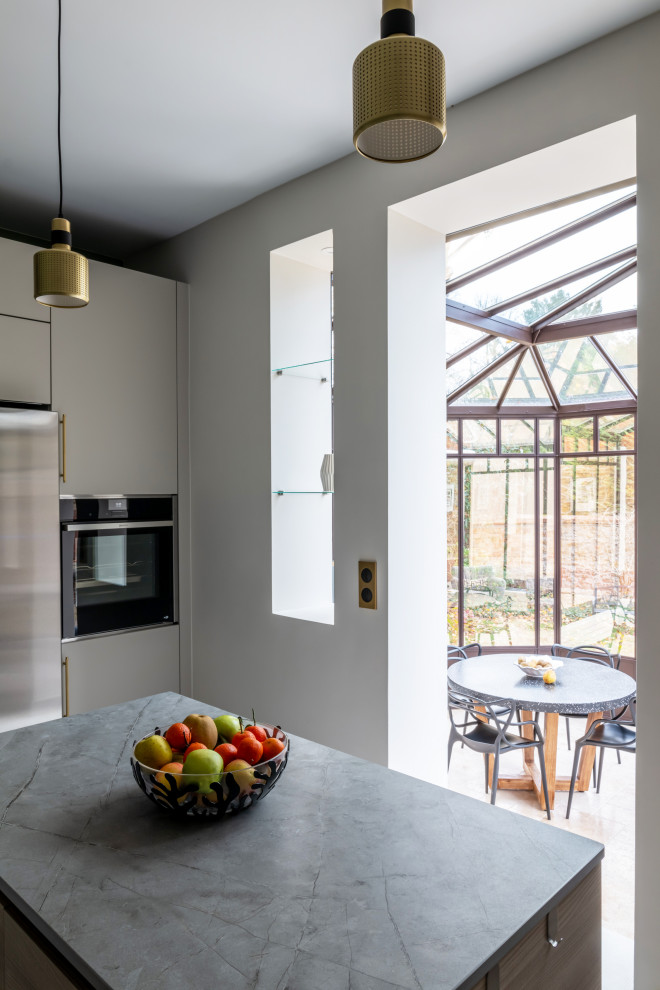Large contemporary l-shaped open plan kitchen in Paris with an undermount sink, beaded inset cabinets, beige cabinets, quartzite benchtops, grey splashback, engineered quartz splashback, panelled appliances, marble floors, with island, white floor and grey benchtop.