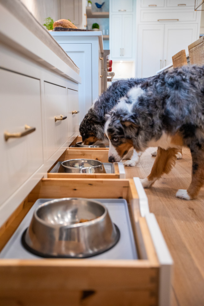 Inspiration for a large transitional u-shaped light wood floor kitchen remodel with an undermount sink, shaker cabinets, white cabinets, quartz countertops, white backsplash, marble backsplash, paneled appliances, two islands and white countertops