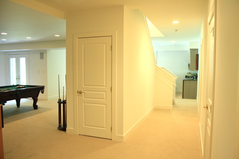 This is an example of a large traditional walk-out basement in DC Metro with white walls, carpet and no fireplace.