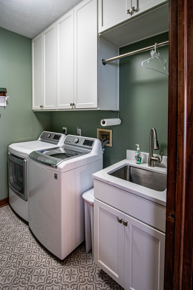 クリーブランドにあるお手頃価格の小さなトランジショナルスタイルのおしゃれな洗濯室 (I型、アンダーカウンターシンク、フラットパネル扉のキャビネット、白いキャビネット、クオーツストーンカウンター、緑の壁、セラミックタイルの床、左右配置の洗濯機・乾燥機、白いキッチンカウンター) の写真