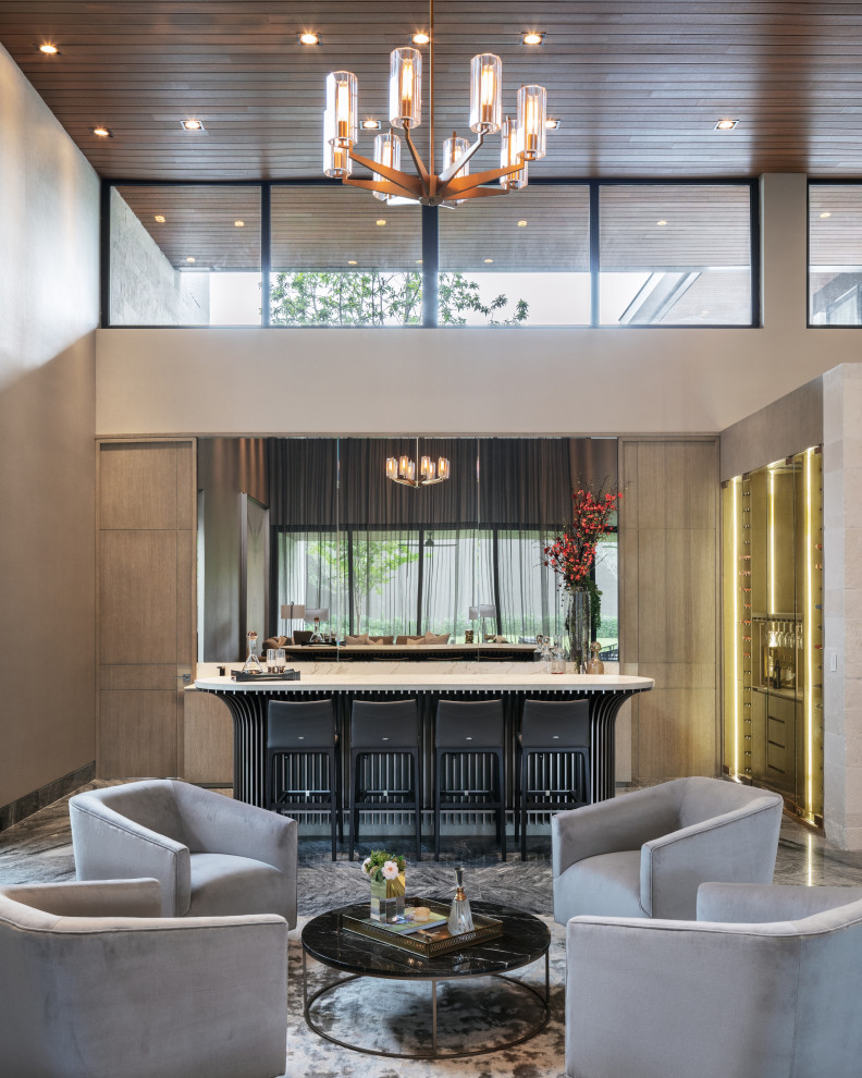 This is an example of an expansive contemporary l-shaped seated home bar in Austin with flat-panel cabinets, beige cabinets, mirror splashback, grey floor and white benchtop.
