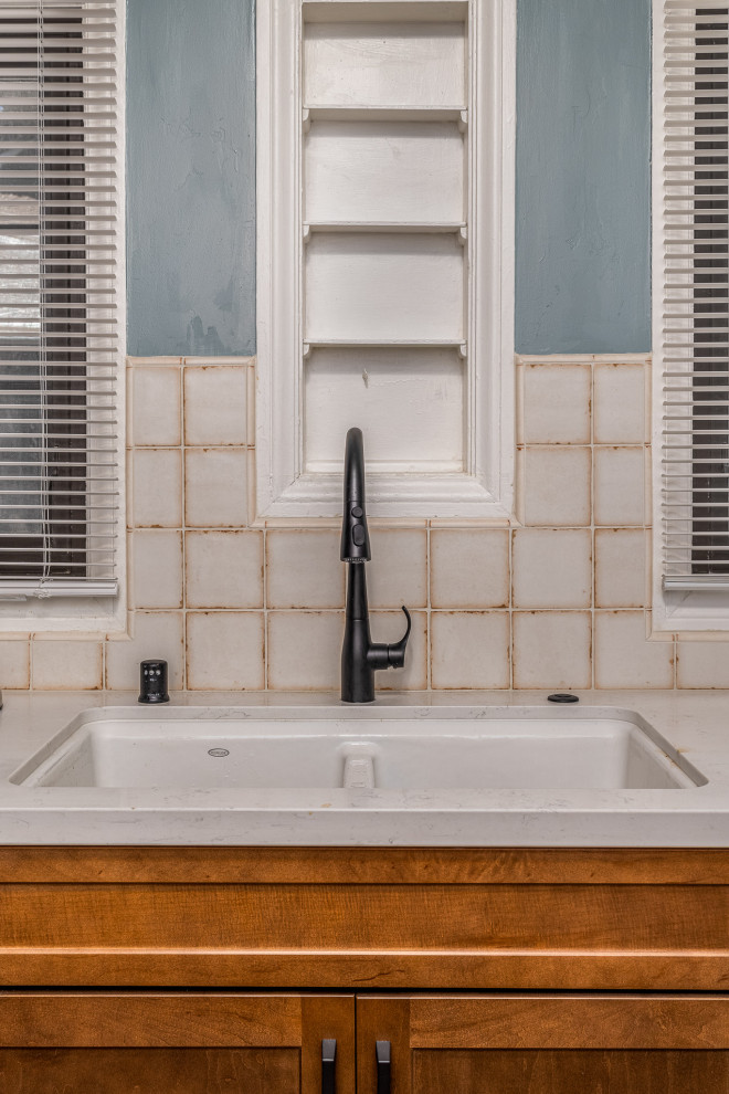 Bild på ett avskilt, litet medelhavsstil vit vitt kök, med en undermonterad diskho, luckor med infälld panel, skåp i mörkt trä, bänkskiva i kvarts, vitt stänkskydd, stänkskydd i porslinskakel, svarta vitvaror och klinkergolv i terrakotta