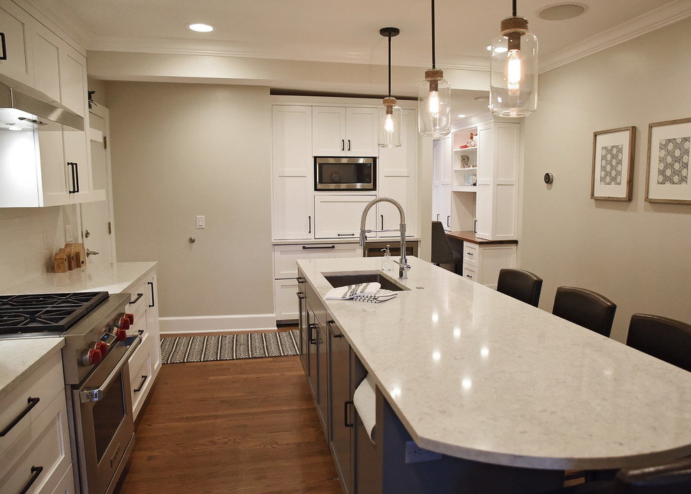Enclosed kitchen - mid-sized transitional medium tone wood floor and brown floor enclosed kitchen idea with an undermount sink, flat-panel cabinets, white cabinets, quartz countertops, white backsplash, ceramic backsplash, stainless steel appliances, an island and gray countertops