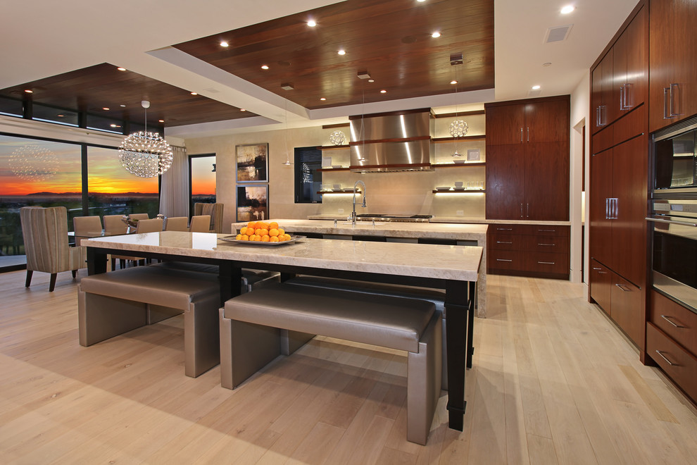 Large contemporary l-shaped eat-in kitchen in Orange County with flat-panel cabinets, dark wood cabinets, limestone benchtops, with island, an undermount sink, beige splashback, stainless steel appliances, light hardwood floors, ceramic splashback and brown floor.
