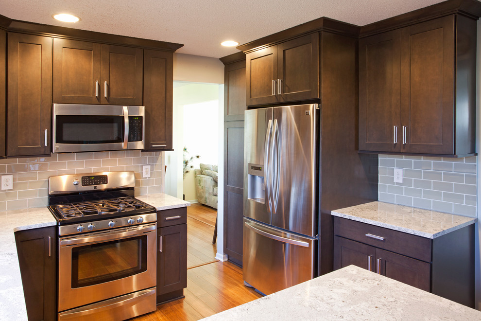 Mid-sized transitional u-shaped medium tone wood floor eat-in kitchen photo in Minneapolis with an undermount sink, flat-panel cabinets, dark wood cabinets, gray backsplash, glass tile backsplash, stainless steel appliances and a peninsula