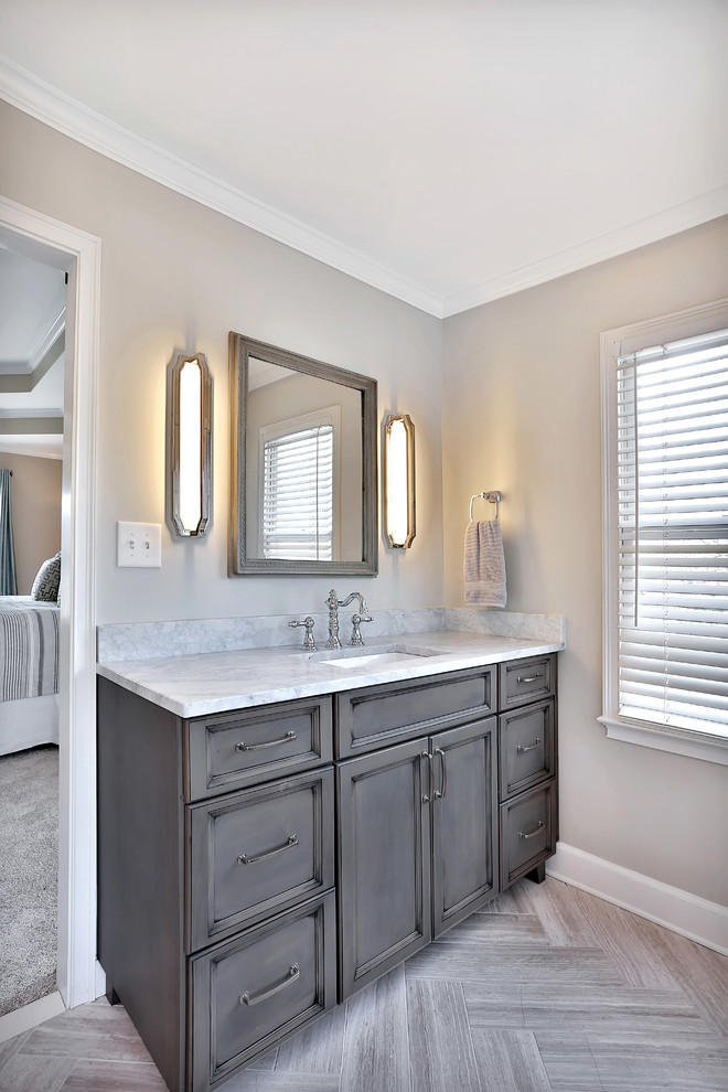 This is an example of a large traditional master bathroom in Atlanta with recessed-panel cabinets, grey cabinets, a freestanding tub, an alcove shower, beige tile, porcelain tile, beige walls, porcelain floors, an undermount sink, marble benchtops, beige floor and a hinged shower door.