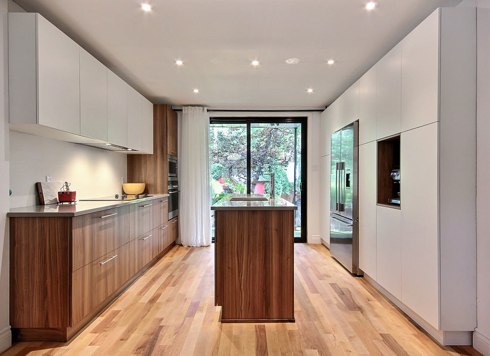 Photo of a mid-sized modern galley open plan kitchen in Montreal with an undermount sink, flat-panel cabinets, medium wood cabinets, quartz benchtops, white appliances, medium hardwood floors, with island, brown floor and beige benchtop.