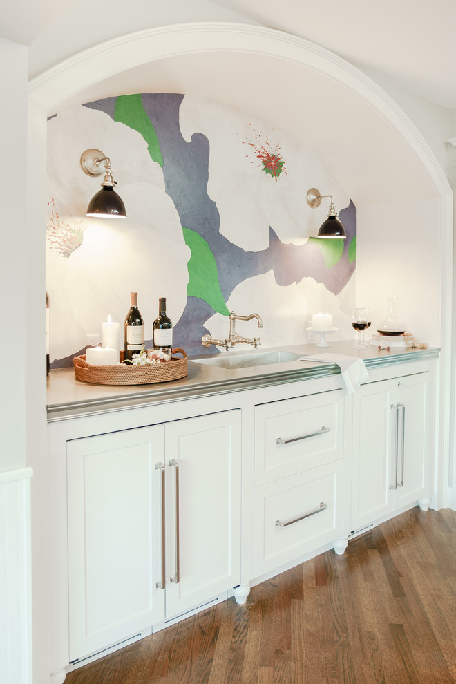 This is an example of a small contemporary single-wall wet bar in Providence with an integrated sink, shaker cabinets, white cabinets, wood benchtops, multi-coloured splashback, medium hardwood floors, brown floor and brown benchtop.