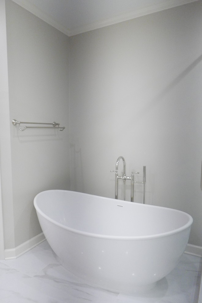 Inspiration for a large transitional master white tile and porcelain tile porcelain tile and white floor freestanding bathtub remodel with shaker cabinets, white cabinets, a two-piece toilet, beige walls, an undermount sink, marble countertops, a hinged shower door and white countertops