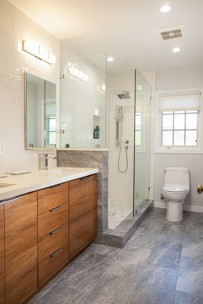 Photo of a medium sized classic shower room bathroom in Los Angeles with flat-panel cabinets, medium wood cabinets, an alcove shower, a one-piece toilet, grey tiles, metro tiles, white walls, marble flooring, a submerged sink, engineered stone worktops, blue floors, an open shower, white worktops, double sinks and a built in vanity unit.