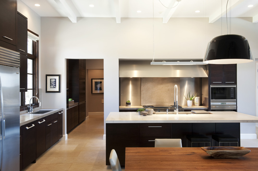 This is an example of a large contemporary l-shaped eat-in kitchen in Austin with stainless steel appliances, flat-panel cabinets, dark wood cabinets, beige splashback, stone slab splashback, with island, an undermount sink, travertine floors, quartz benchtops and beige floor.