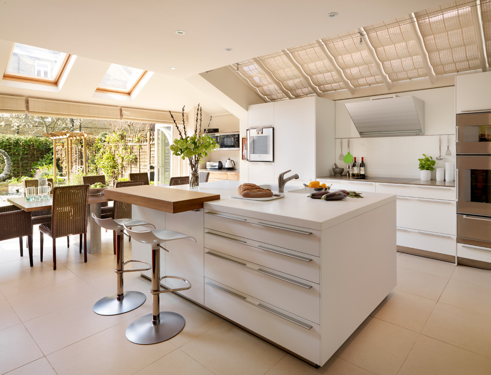Design ideas for a large contemporary l-shaped eat-in kitchen in Wiltshire with flat-panel cabinets, white cabinets, stainless steel appliances, an integrated sink, solid surface benchtops, white splashback, glass sheet splashback, porcelain floors and with island.
