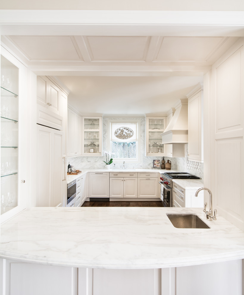 Photo of a mid-sized traditional u-shaped kitchen in Houston with a drop-in sink, raised-panel cabinets, white cabinets, marble benchtops, white splashback, mirror splashback, stainless steel appliances, dark hardwood floors and no island.
