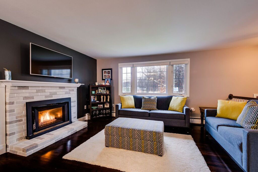 This is an example of a mid-sized transitional open concept family room in Boston with grey walls, dark hardwood floors, a standard fireplace, a plaster fireplace surround, a wall-mounted tv and brown floor.