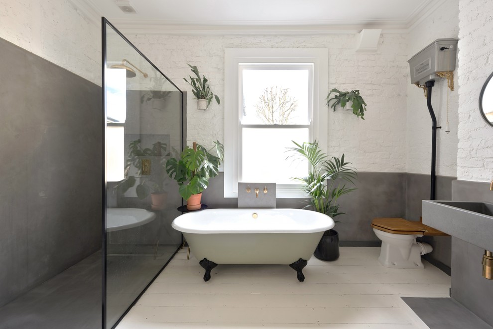 This is an example of a large scandinavian wet room bathroom in London with a freestanding tub, a two-piece toilet, white walls, painted wood floors, a wall-mount sink, white floor and an open shower.