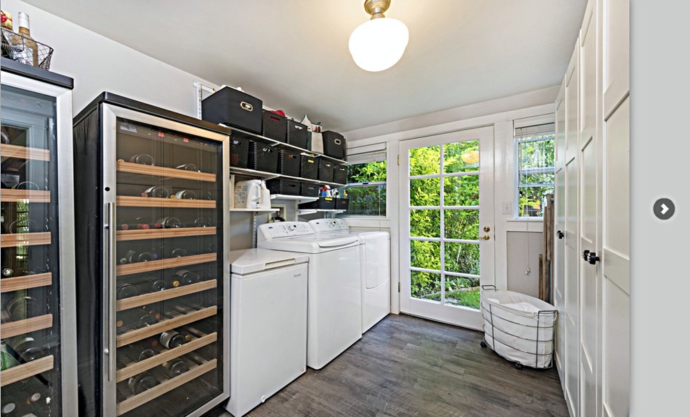 This is an example of a large traditional utility room in San Francisco with white cabinets, grey walls, dark hardwood floors and a side-by-side washer and dryer.