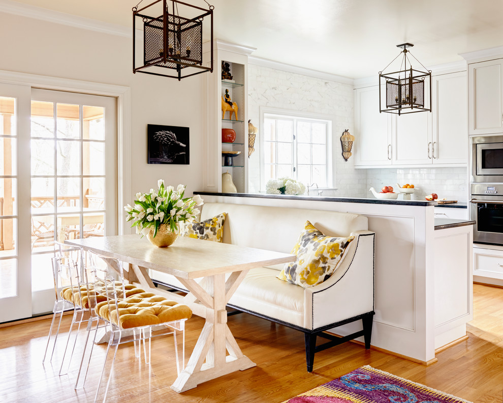 This is an example of a transitional kitchen/dining combo in Charlotte with beige walls and medium hardwood floors.