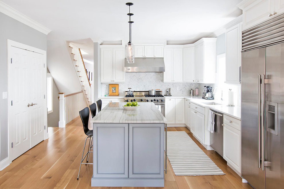 Photo of a transitional kitchen in Chicago with a single-bowl sink, solid surface benchtops, stone tile splashback, stainless steel appliances, light hardwood floors, raised-panel cabinets, white cabinets, white splashback and with island.