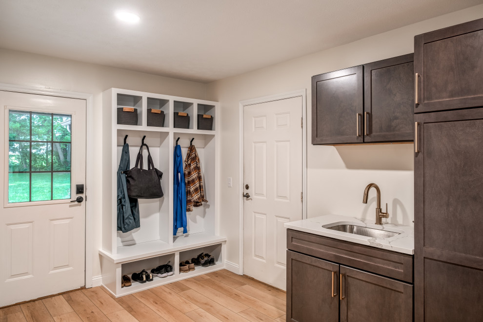 Inspiration for a mid-sized transitional u-shaped utility room in Other with an undermount sink, shaker cabinets, dark wood cabinets, quartz benchtops, white walls, vinyl floors, a stacked washer and dryer, beige floor and white benchtop.