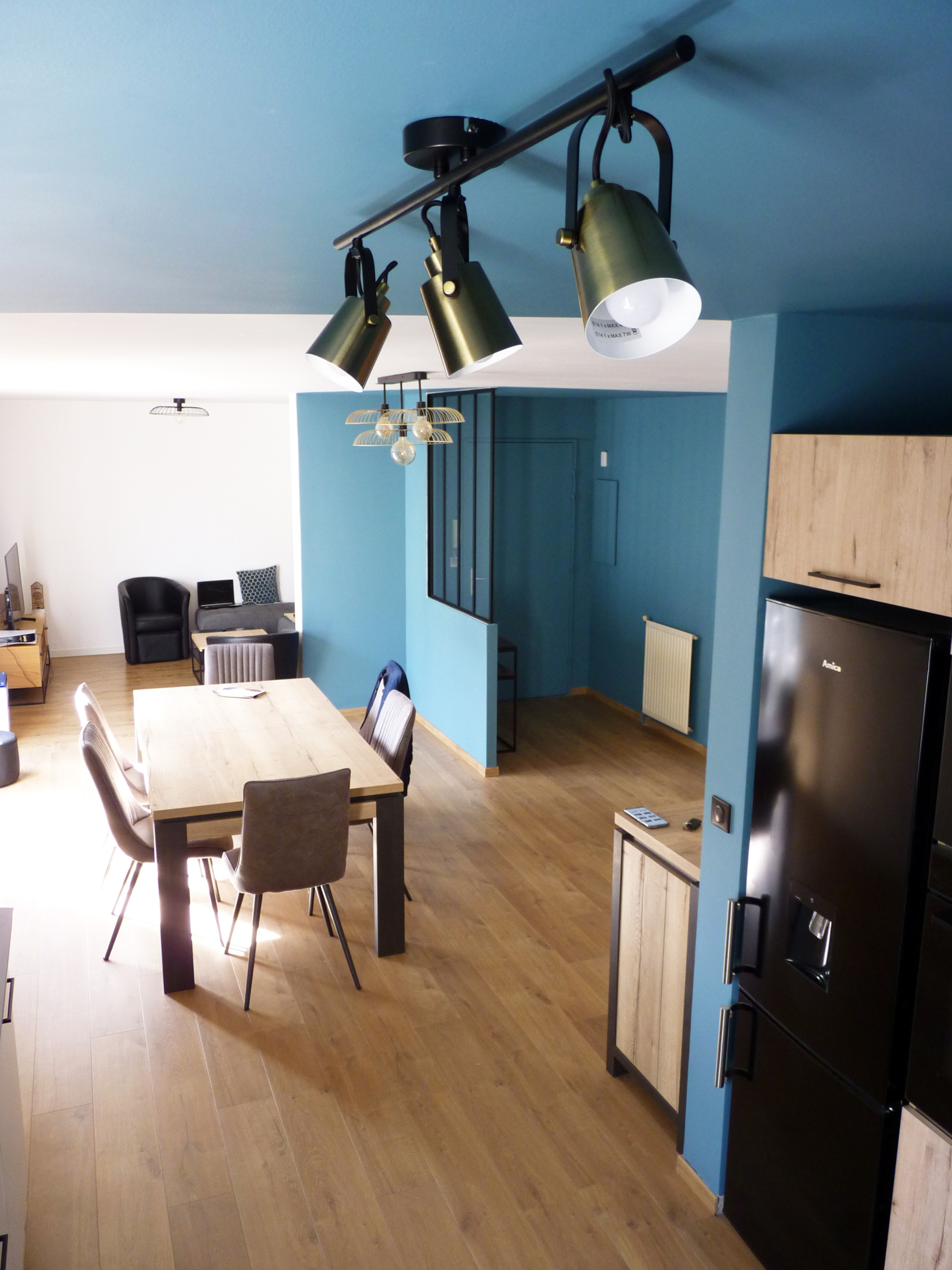 Vue de la cuisine vers l'entrée. Les luminaires en laiton viennent habiller le plafond bleu.