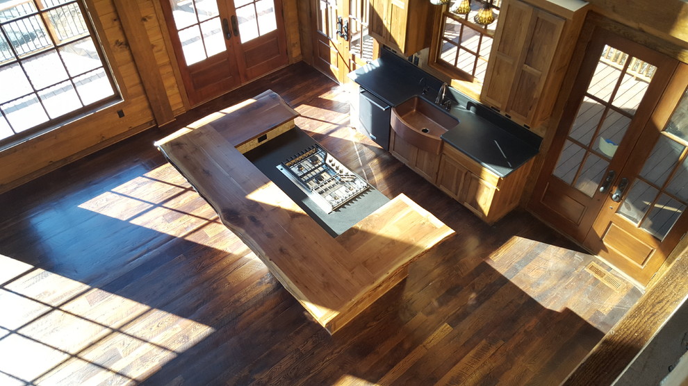 Example of a mid-sized mountain style dark wood floor kitchen design in Atlanta with a farmhouse sink, shaker cabinets, medium tone wood cabinets, granite countertops, beige backsplash, ceramic backsplash, stainless steel appliances and an island