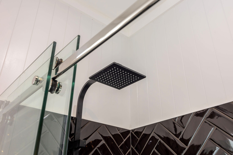 Идея дизайна: маленькая ванная комната в стиле фьюжн с плоскими фасадами, белыми фасадами, угловым душем, унитазом-моноблоком, черной плиткой, керамической плиткой, серыми стенами, полом из керамогранита, накладной раковиной, столешницей из искусственного камня, серым полом, душем с раздвижными дверями, белой столешницей, тумбой под одну раковину, подвесной тумбой и панелями на части стены для на участке и в саду