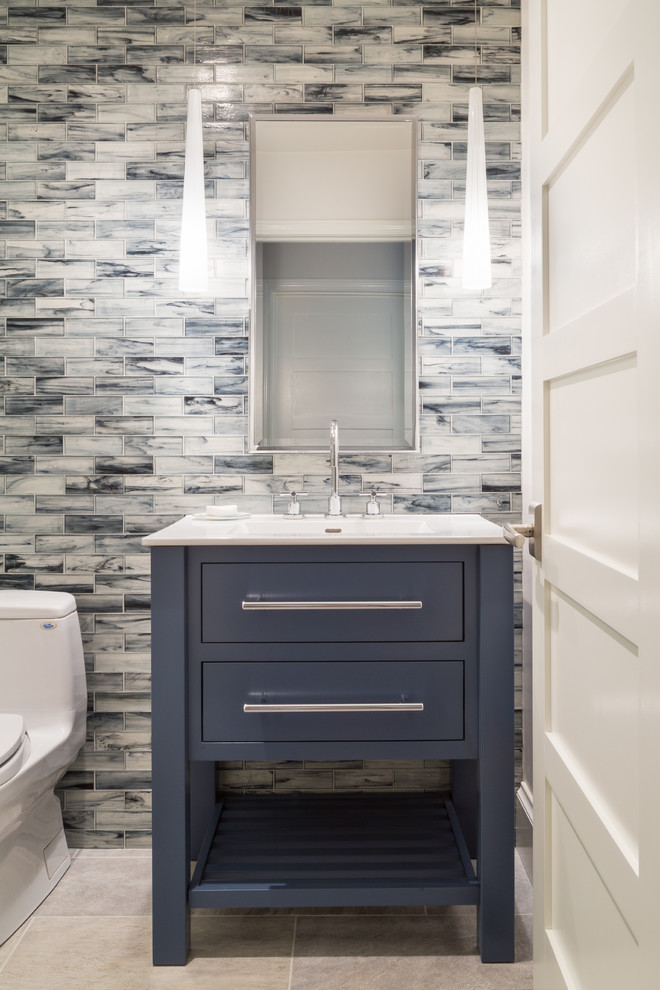 Inspiration for a mid-sized contemporary 3/4 bathroom in Providence with flat-panel cabinets, blue cabinets, a one-piece toilet, blue tile, stone tile, blue walls, porcelain floors, a drop-in sink and solid surface benchtops.
