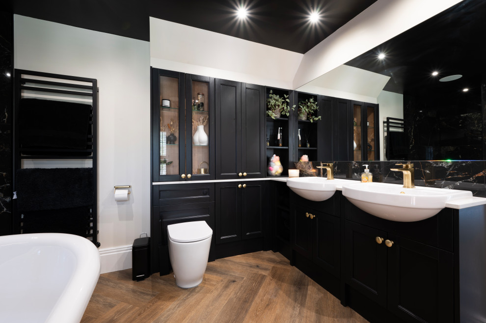 Photo of a mid-sized modern master bathroom in Kent with recessed-panel cabinets, black cabinets, a freestanding tub, an open shower, a one-piece toilet, black tile, ceramic tile, white walls, vinyl floors, an integrated sink, brown floor, an open shower, white benchtops, a double vanity and a built-in vanity.