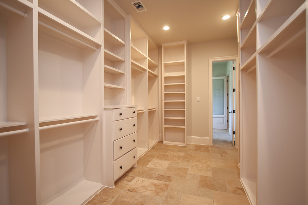 Large contemporary gender-neutral walk-in wardrobe in Houston with flat-panel cabinets, white cabinets, travertine floors and beige floor.