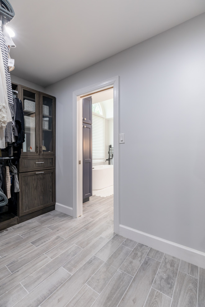 This is an example of a mid-sized contemporary gender-neutral walk-in wardrobe in DC Metro with grey cabinets and grey floor.