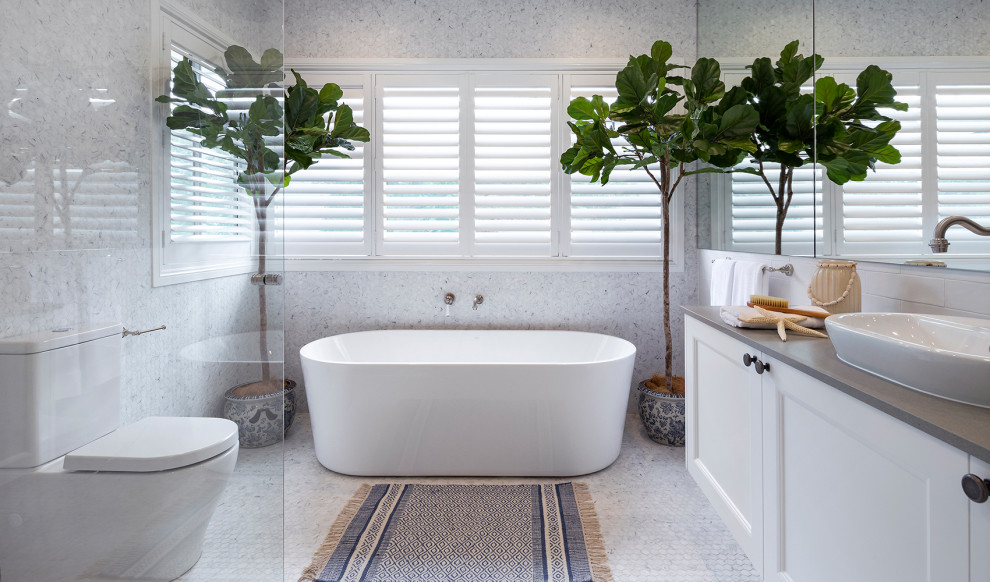 Inspiration for a large beach style master bathroom in Other with recessed-panel cabinets, white cabinets, a freestanding tub, a corner shower, gray tile, a vessel sink, grey floor, an open shower, grey benchtops, a single vanity and a built-in vanity.