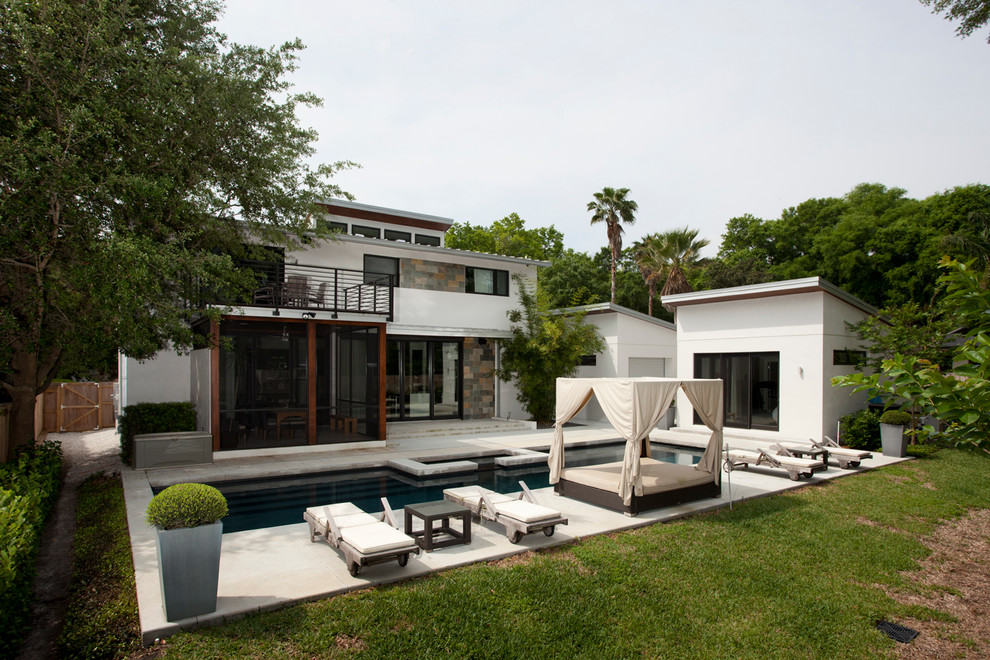 Inspiration for a modern backyard rectangular lap pool in Orlando with a pool house and concrete slab.