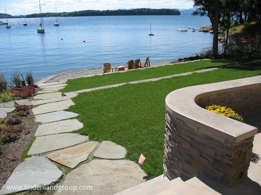 Design ideas for a mid-sized contemporary sloped full sun garden in Burlington with a retaining wall and natural stone pavers.