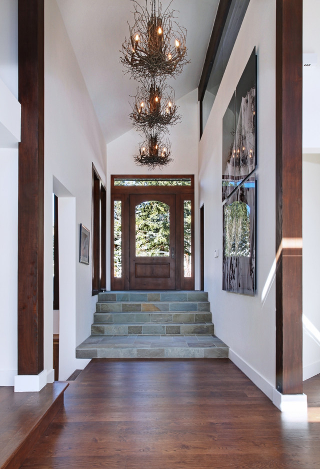 Mid-sized mountain style dark wood floor and brown floor foyer photo with white walls and a dark wood front door