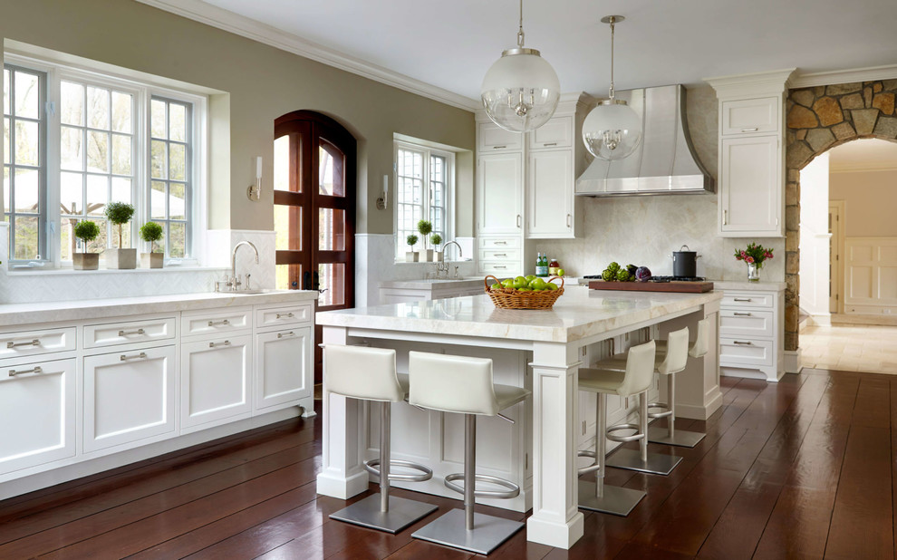 Photo of a traditional l-shaped kitchen in New York with an undermount sink, shaker cabinets, white cabinets, beige splashback, medium hardwood floors, with island and orange floor.