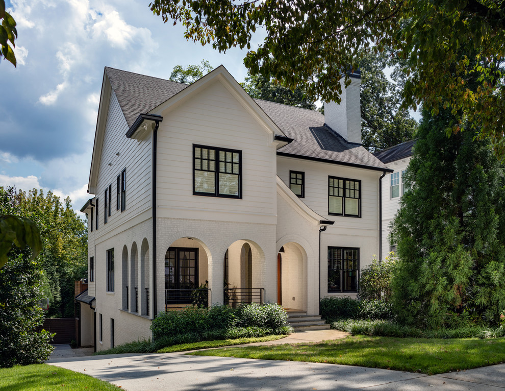 This is an example of a large transitional two-storey white house exterior in Atlanta with mixed siding, a gable roof and a shingle roof.