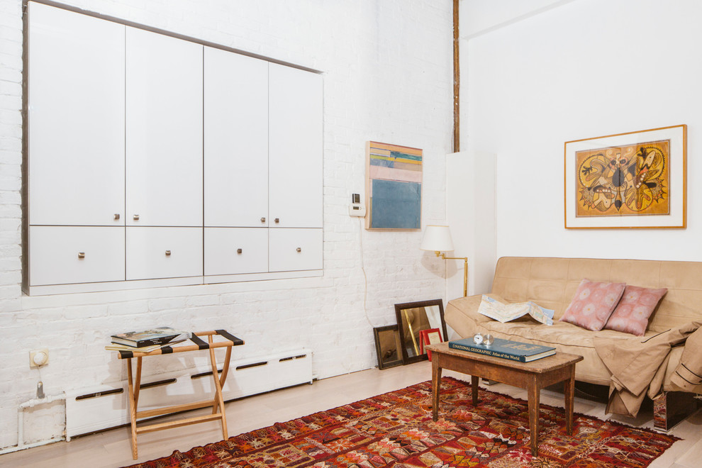 Mid-sized industrial home studio in New York with white walls, light hardwood floors and a built-in desk.