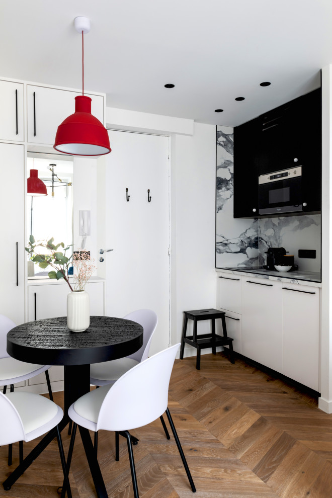 This is an example of a small contemporary single-wall open plan kitchen in Paris with an undermount sink, tile benchtops, black appliances, medium hardwood floors and brown floor.