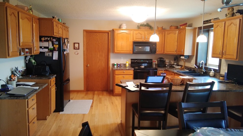 Eat-in kitchen - large transitional u-shaped light wood floor and multicolored floor eat-in kitchen idea in Cedar Rapids with an undermount sink, raised-panel cabinets, dark wood cabinets, granite countertops, metallic backsplash, ceramic backsplash, stainless steel appliances, an island and gray countertops