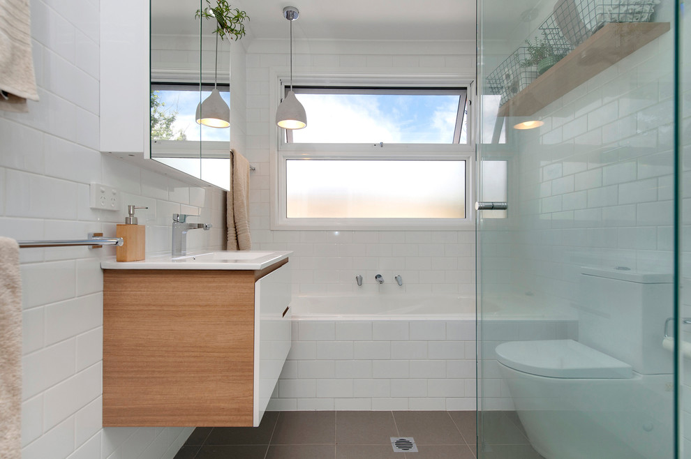 Inspiration for a small midcentury bathroom in Canberra - Queanbeyan with beaded inset cabinets, white cabinets, a drop-in tub, an open shower, a one-piece toilet, white tile, subway tile, white walls, ceramic floors, an integrated sink and solid surface benchtops.