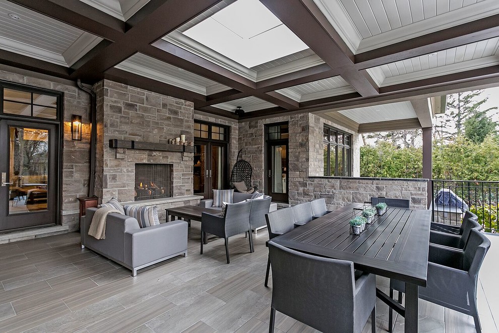 Design ideas for a mid-sized transitional backyard patio in Toronto with tile, a roof extension and with fireplace.
