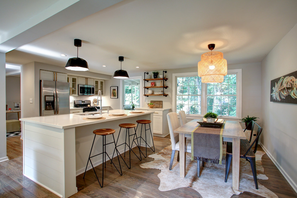 Mid-sized contemporary single-wall eat-in kitchen in Atlanta with an undermount sink, shaker cabinets, white cabinets, quartz benchtops, stainless steel appliances, cork floors, with island, brown floor and white benchtop.