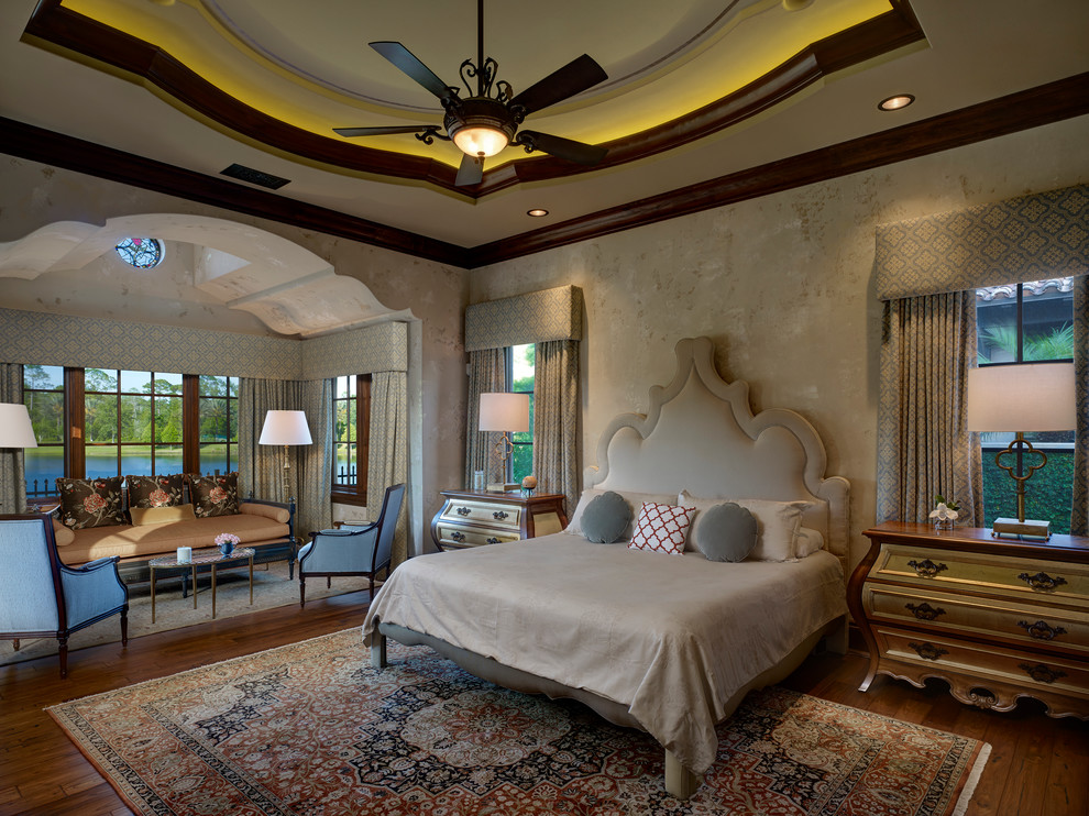 This is an example of an expansive mediterranean master bedroom in Orlando with beige walls, dark hardwood floors, no fireplace and brown floor.