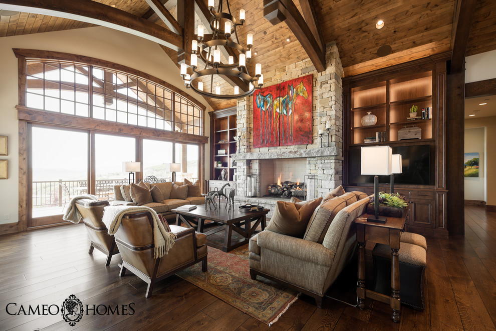 This is an example of a large country open concept family room in Salt Lake City with white walls, dark hardwood floors, a standard fireplace, a stone fireplace surround and a built-in media wall.