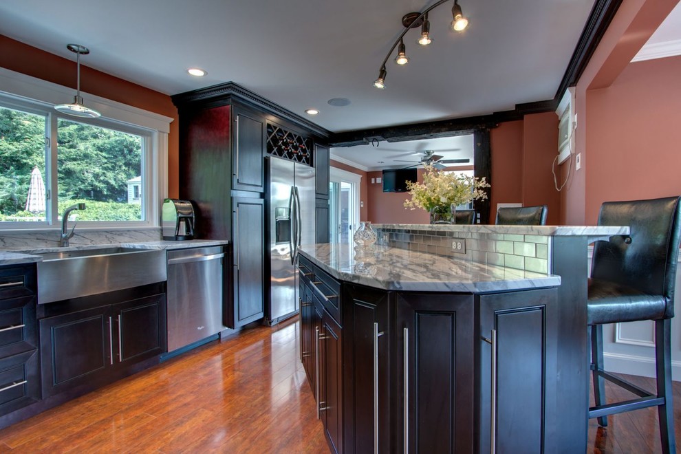 Inspiration for a mid-sized transitional l-shaped medium tone wood floor and brown floor eat-in kitchen remodel in Raleigh with a farmhouse sink, raised-panel cabinets, dark wood cabinets, marble countertops, stainless steel appliances, an island and white countertops