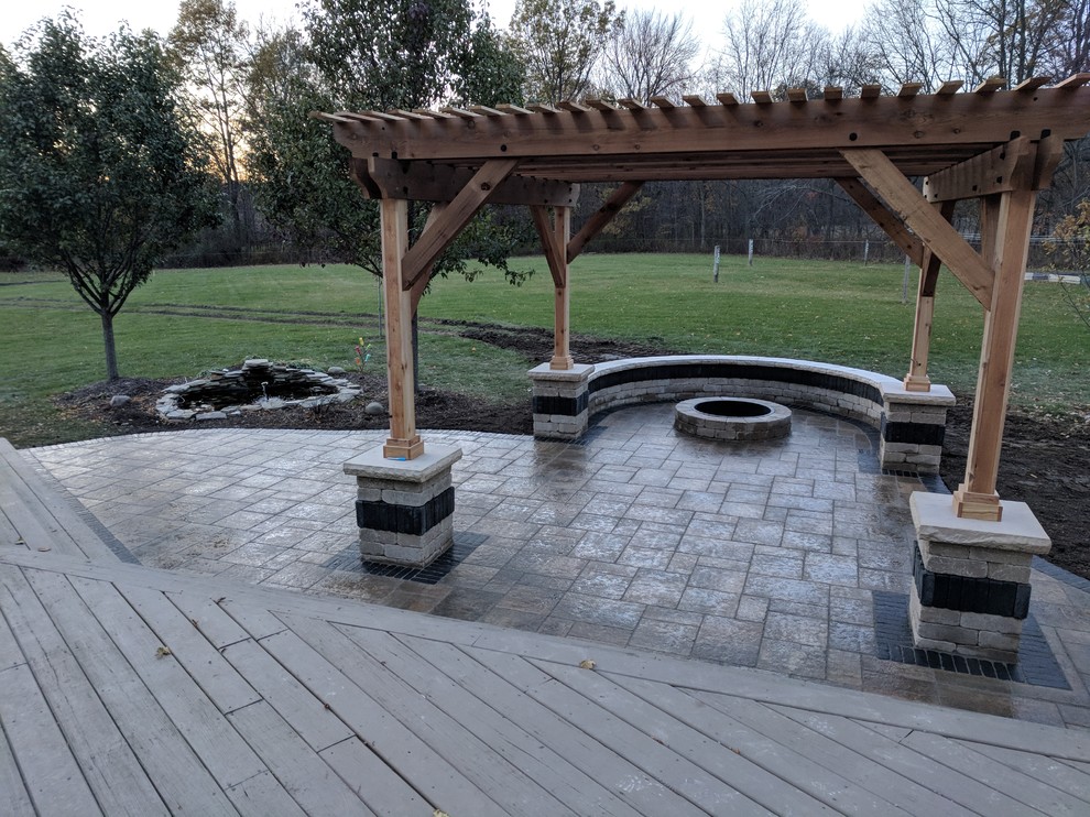 Design ideas for a mid-sized transitional backyard patio in Chicago with a fire feature, stamped concrete and a pergola.