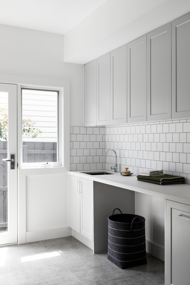 Design ideas for a galley utility room in Melbourne with an undermount sink, shaker cabinets, grey cabinets, quartz benchtops, white walls, porcelain floors, grey floor and white benchtop.