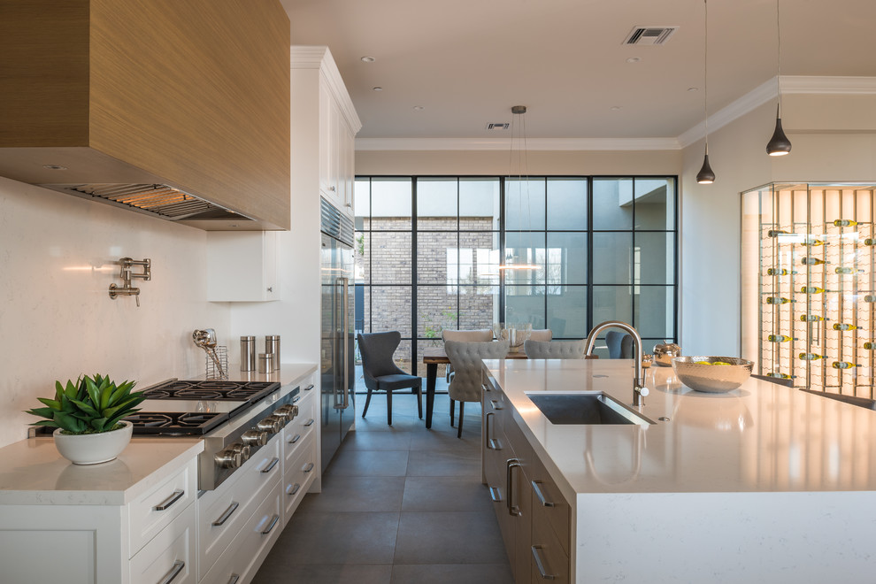 Transitional galley gray floor eat-in kitchen photo in Phoenix with an undermount sink, shaker cabinets, medium tone wood cabinets, white backsplash, stainless steel appliances, an island and white countertops